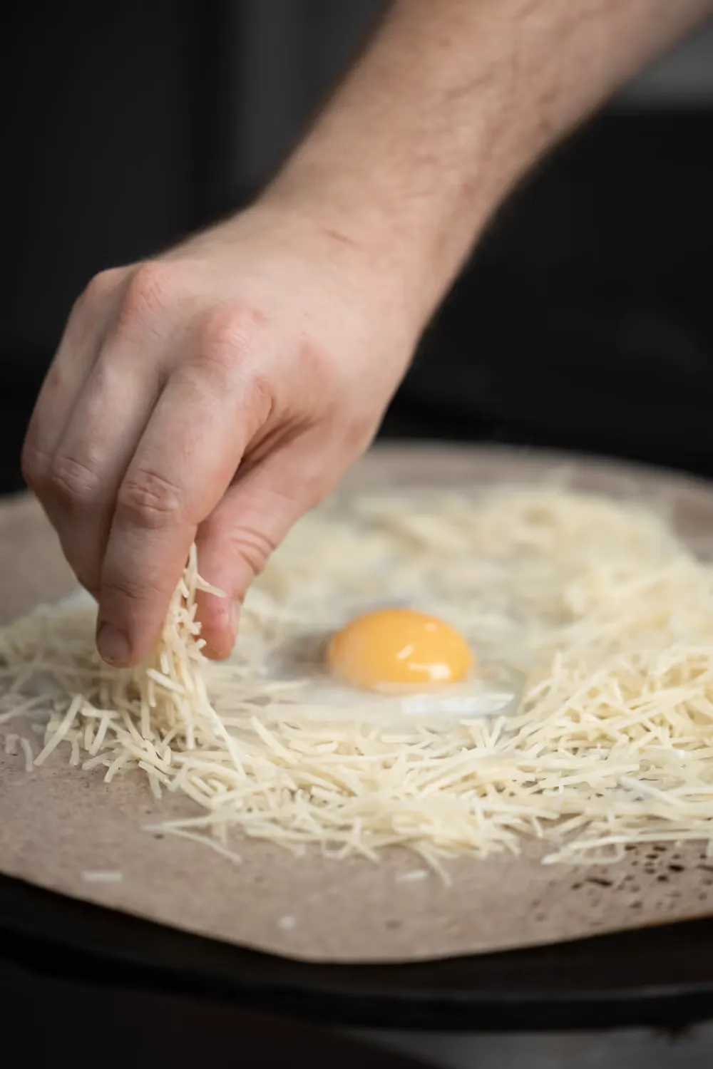 Emmental râpé autour d'un œuf sur une galette
